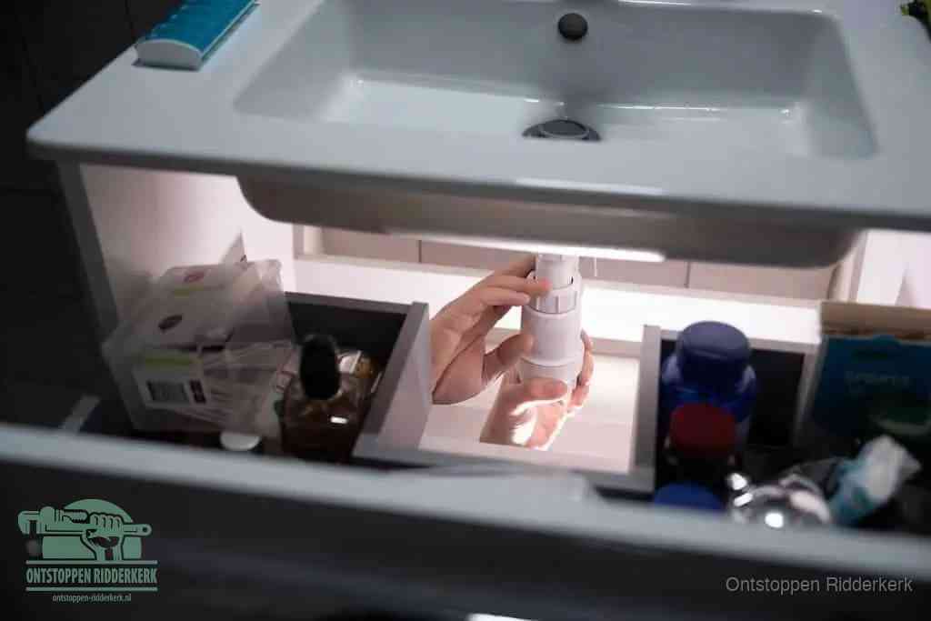 Een pompfles met zeep boven een wastafel, de heet water en afwasmiddel-methode om een vetprop in de afvoer los te maken in Ridderkerk