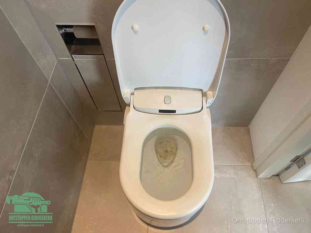 Een wit hangtoilet waarin een prop wc-papier op het water blijft drijven, een duidelijk signaal van een verstopte wc in Ridderkerk