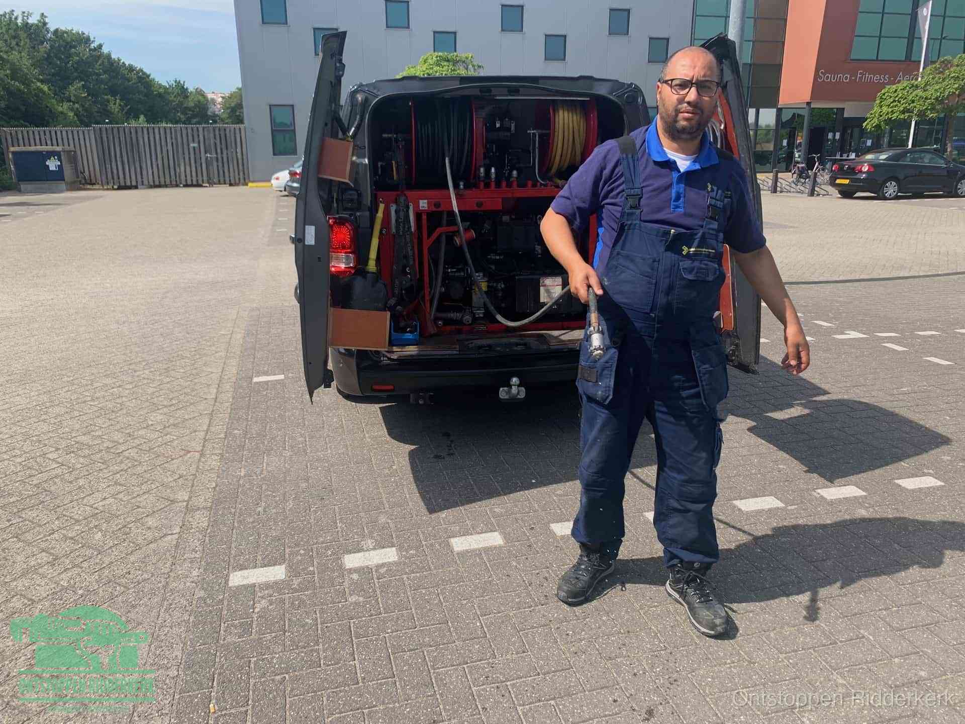 Een monteur bij zijn bestelbus met een hogedruk- en rioolreinigingsunit, klaar om de oorzaak van terugkerende wc-verstoppingen aan te pakken in Ridderkerk