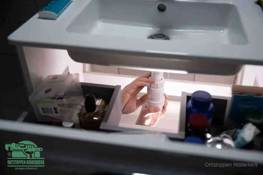 Een pompfles met zeep boven een wastafel in de toiletruimte, de warm water en afwasmiddel-methode om de wc te ontstoppen in Ridderkerk
